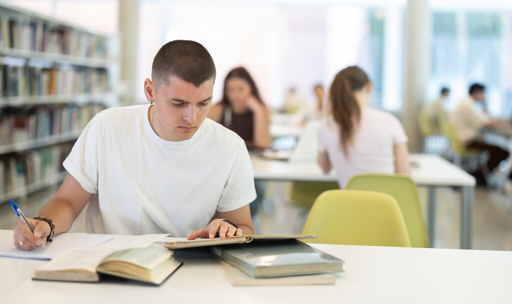 Jovem em biblioteca estudando sobre ortoépia e fonética.