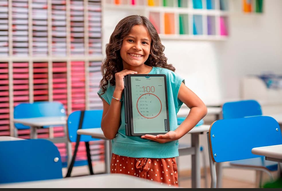 Aluna segurando material Kumon em sala de aula.