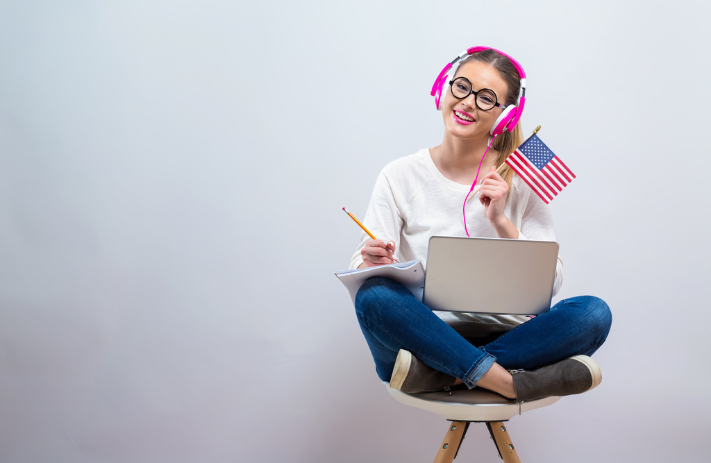 Mulher estudando e segurando bandeira dos Estados Unidos, representando quanto tempo leva para aprender inglês.