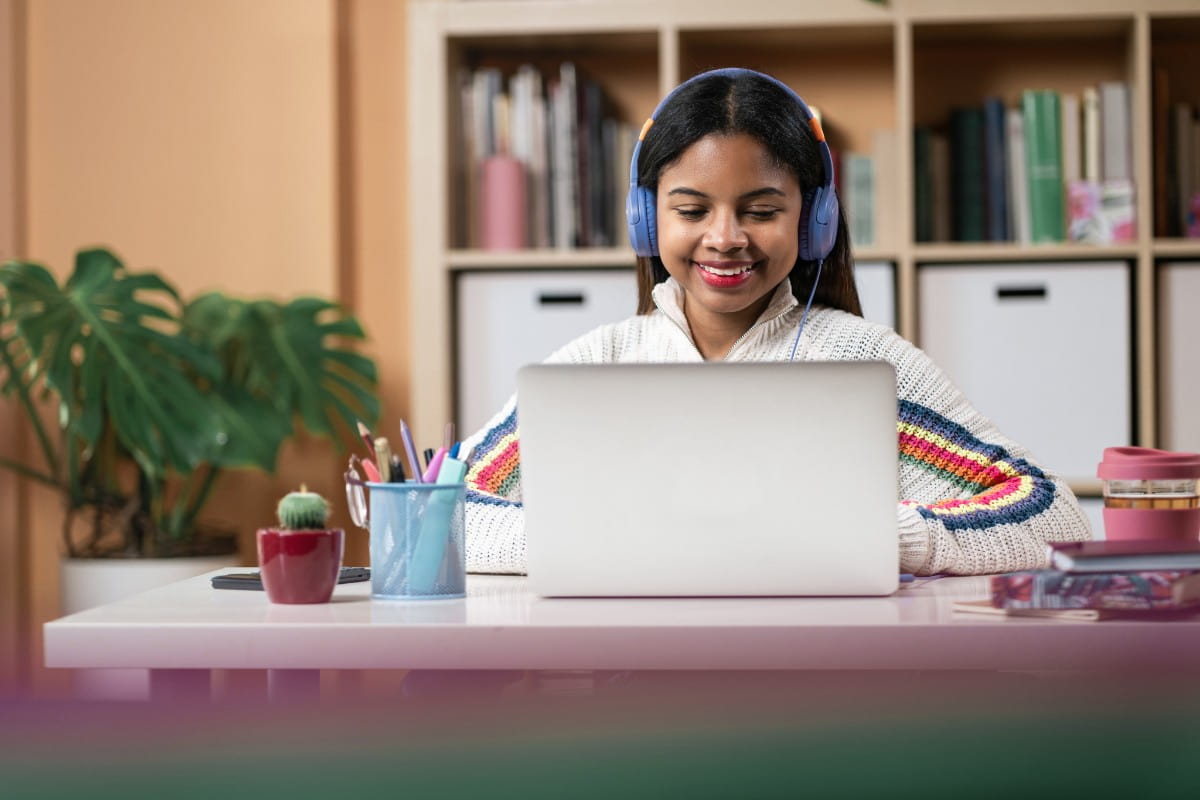 joven con audífonos mirando una laptop en un escritorio