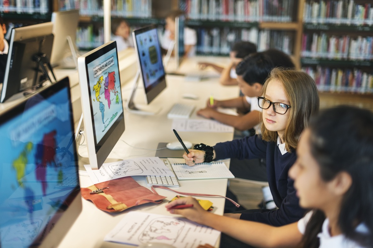 Educação digital com estudantes utilizando computadores durante atividade escolar 