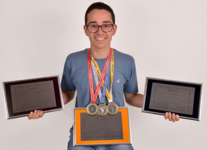Aluno do Kumon segurando certificados e medalhas de conquistas acadêmicas