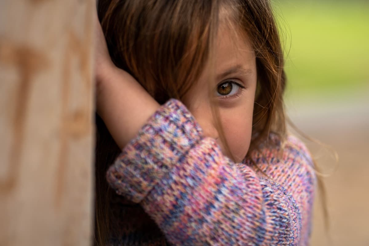 Menina tímida observando uma situação ao seu redor Criança pensativa demonstrando sinais de timidez