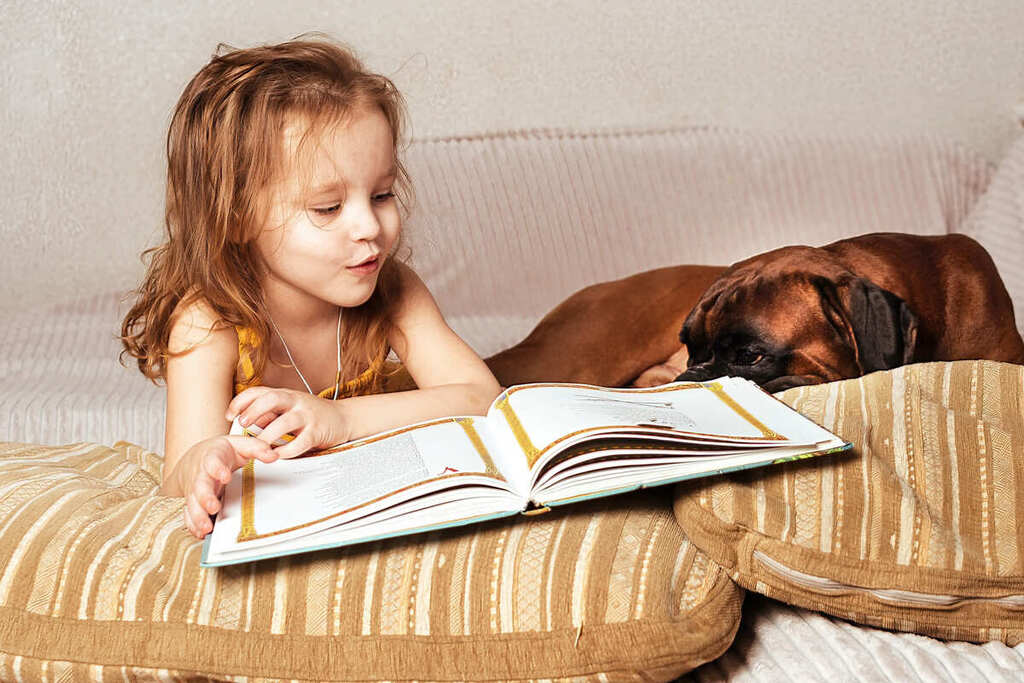 Criança lendo livro infantil educativo.