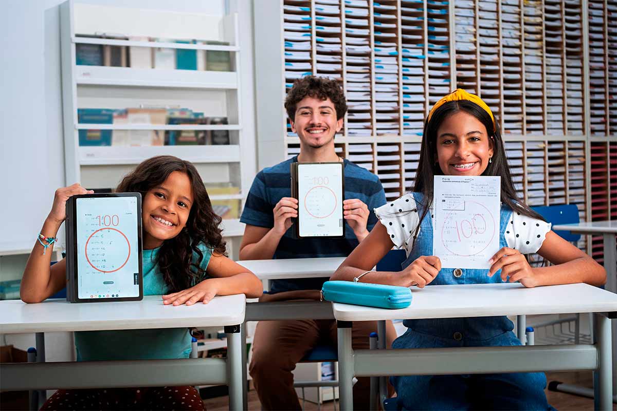 Três alunos felizes mostrando a nota cem que conquistou